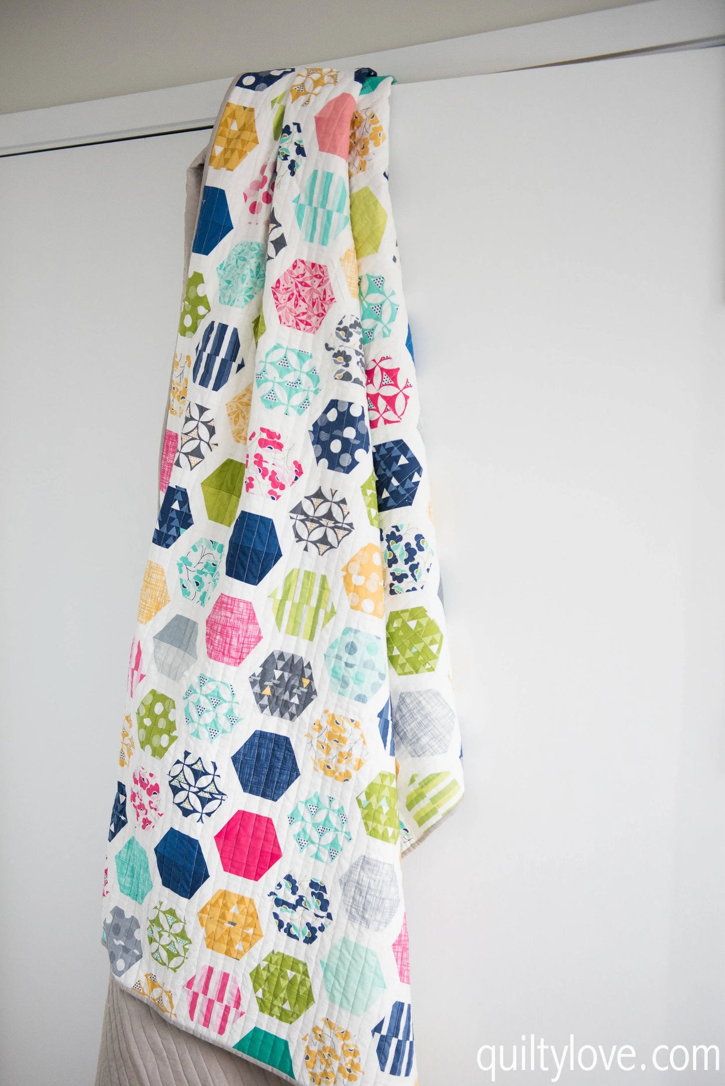 Colorful quilt with geometric pattern hanging on a white wall