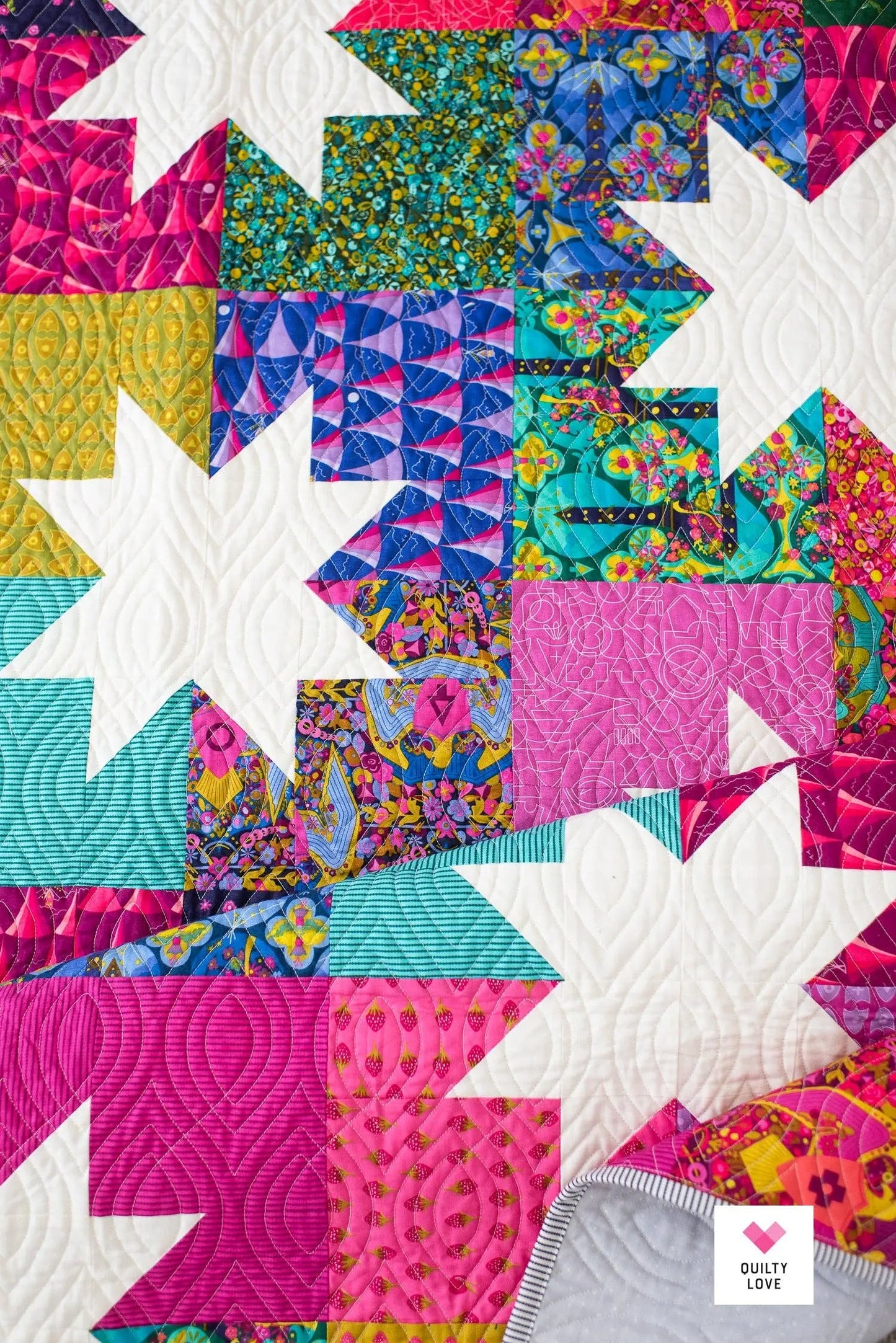 Colorful quilt with star patterns and 'Quilty Love' branding.