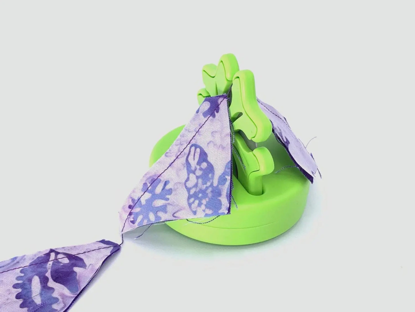 Green cutting tool with old rotary blade showing cutting fabric pieces apart