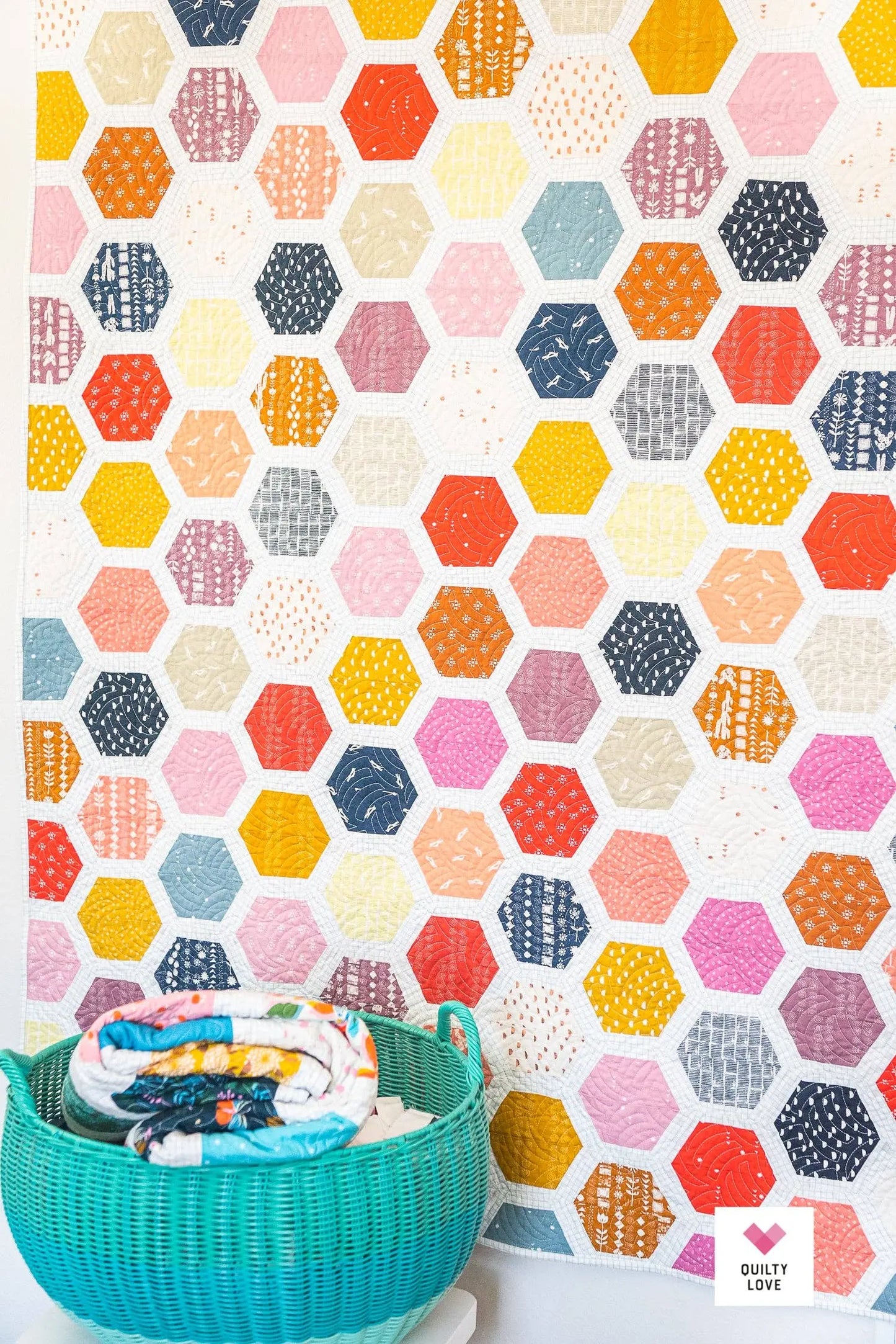 Colorful hexagonal patterned fabric with a teal basket containing baby items.