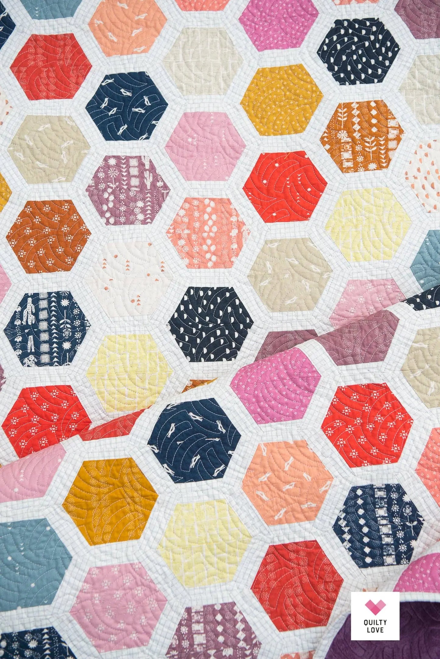 Hexagonal quilt pattern with various colors and patterns on a white background