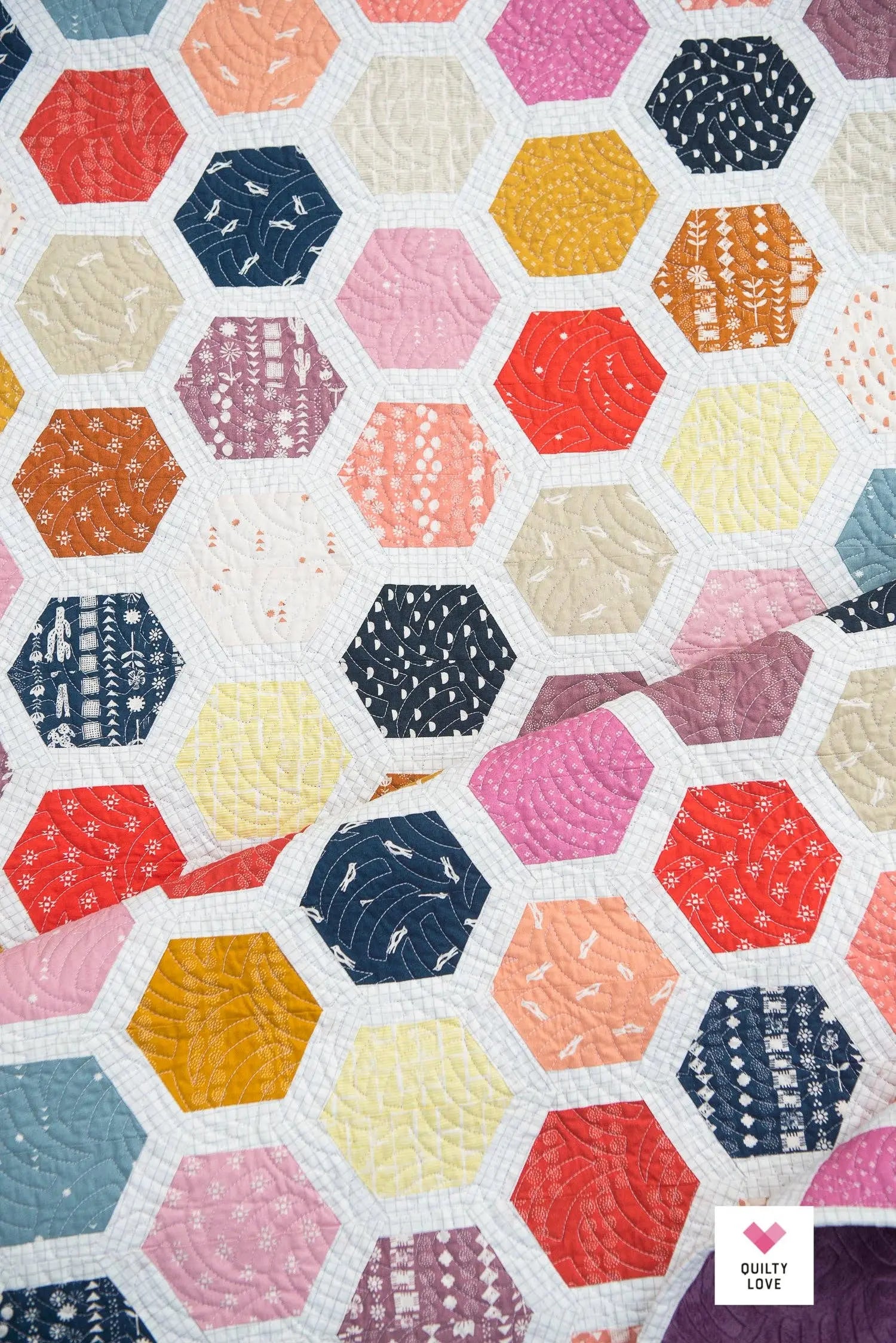 Hexagonal quilt pattern with various colors and patterns on a white background