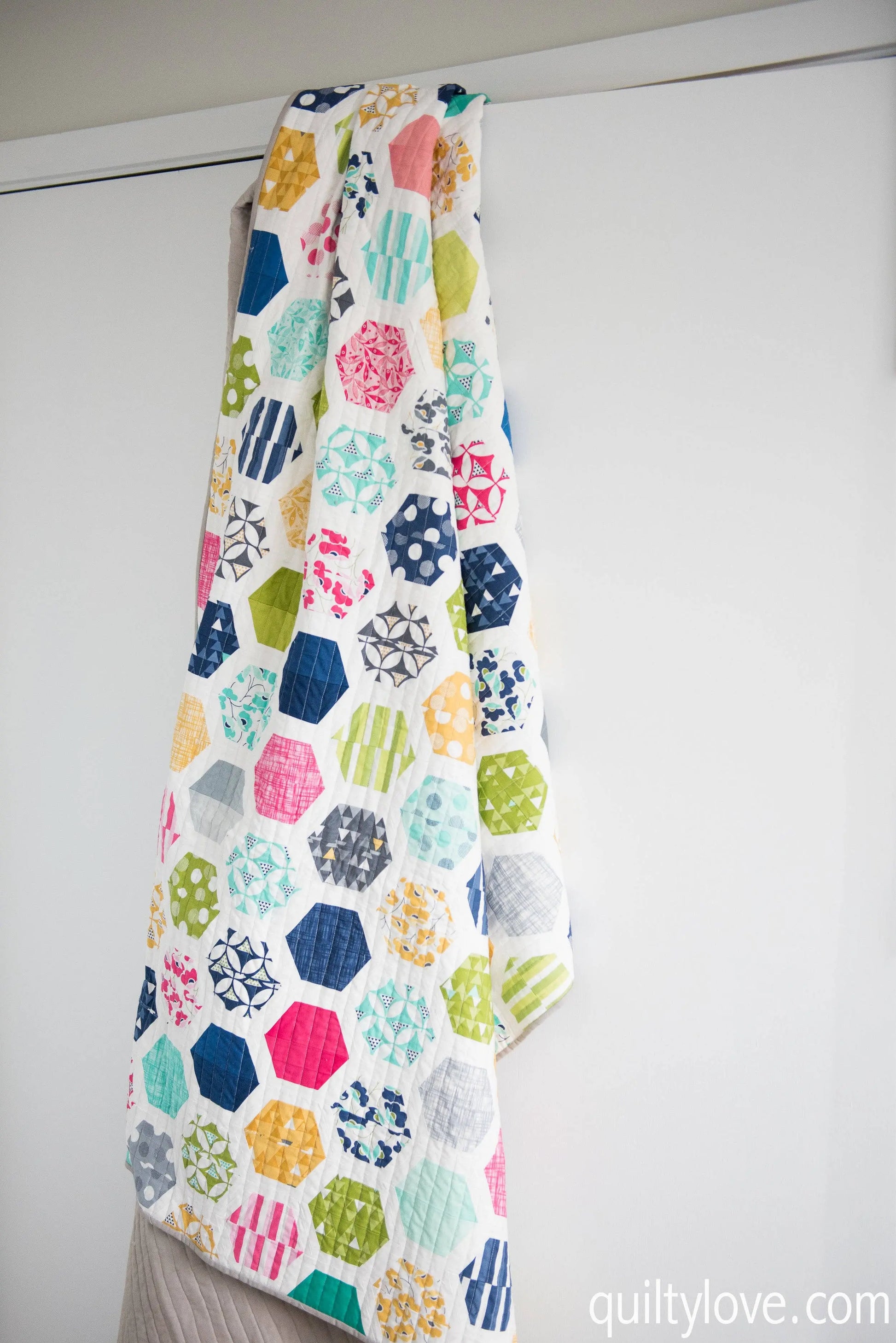 Colorful quilt with geometric pattern hanging on a white wall