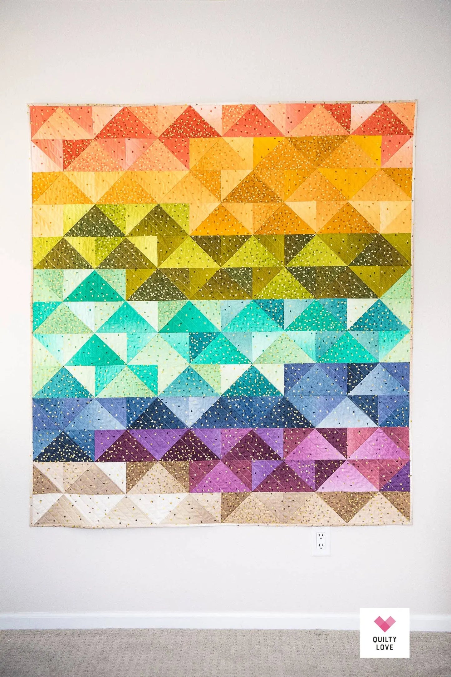 Colorful geometric triangle pattern quilt on a white wall