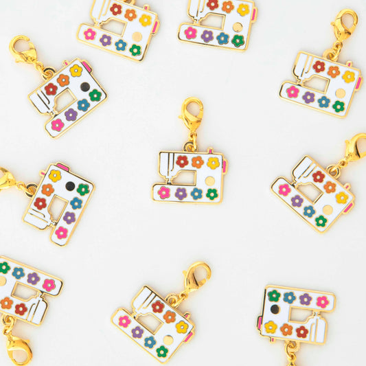 Colorful sewing machine charm pendants on a white background
