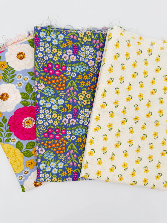 Three floral fabric swatches of a fat quarter bundle in different patterns on a white background