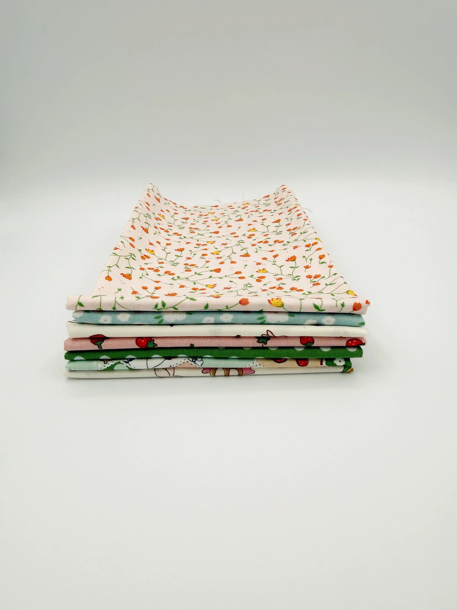 Stack of fabric swatches with various patterns on a light gray background