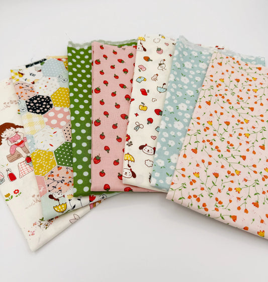 Set of colorful fabric fat quarters with various patterns on a white background