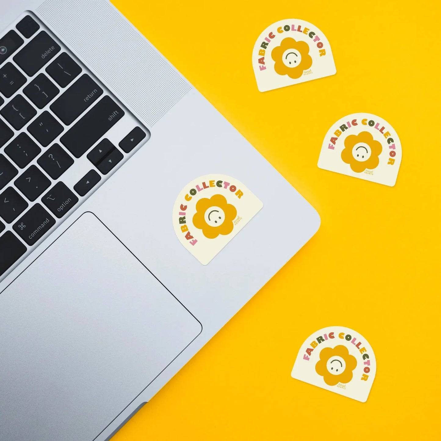 Laptop with 'Fabric Collector' stickers on a yellow background