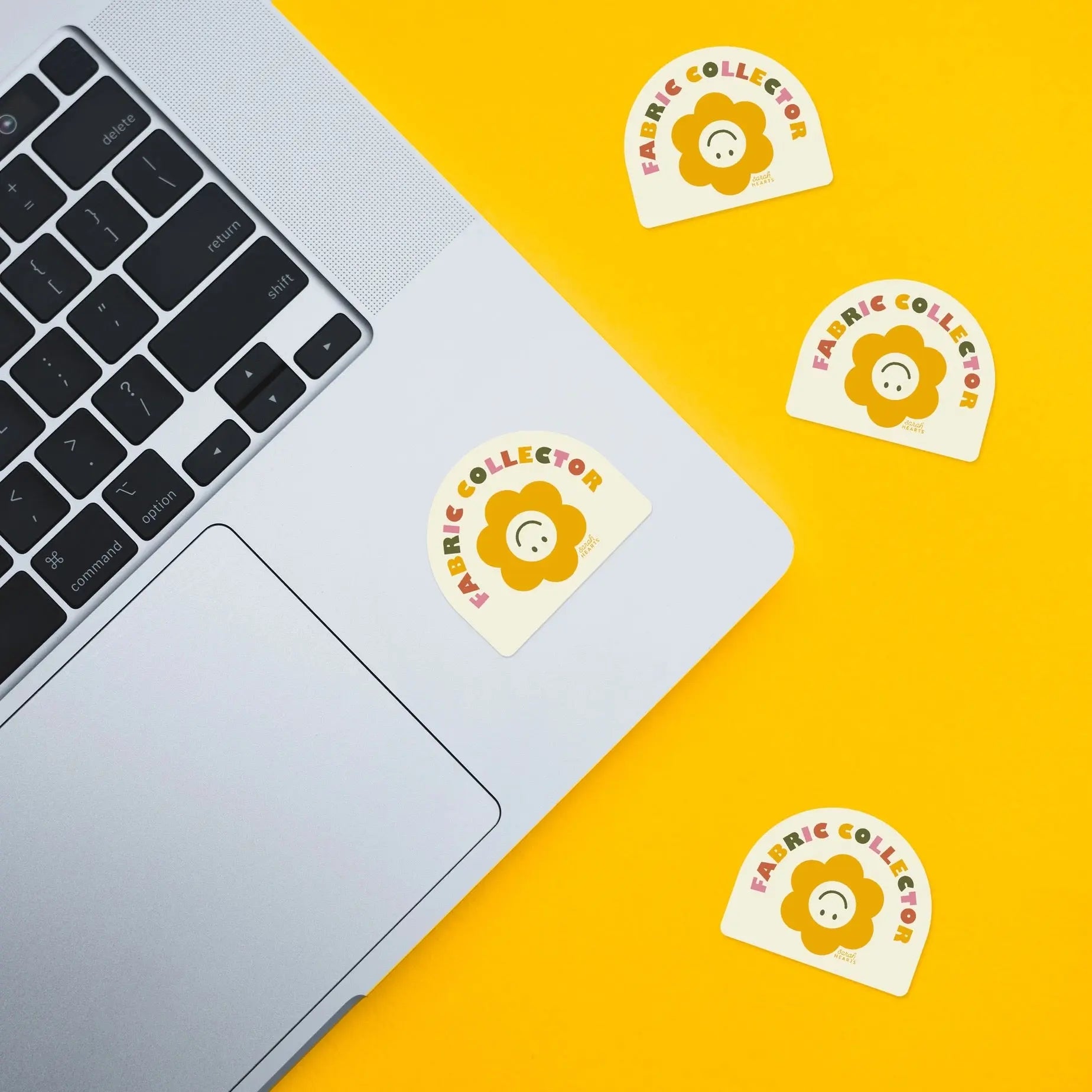 Laptop with 'Fabric Collector' stickers on a yellow background