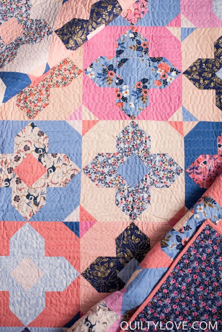 Quilt with floral patterns in pink, blue, and navy on a white background