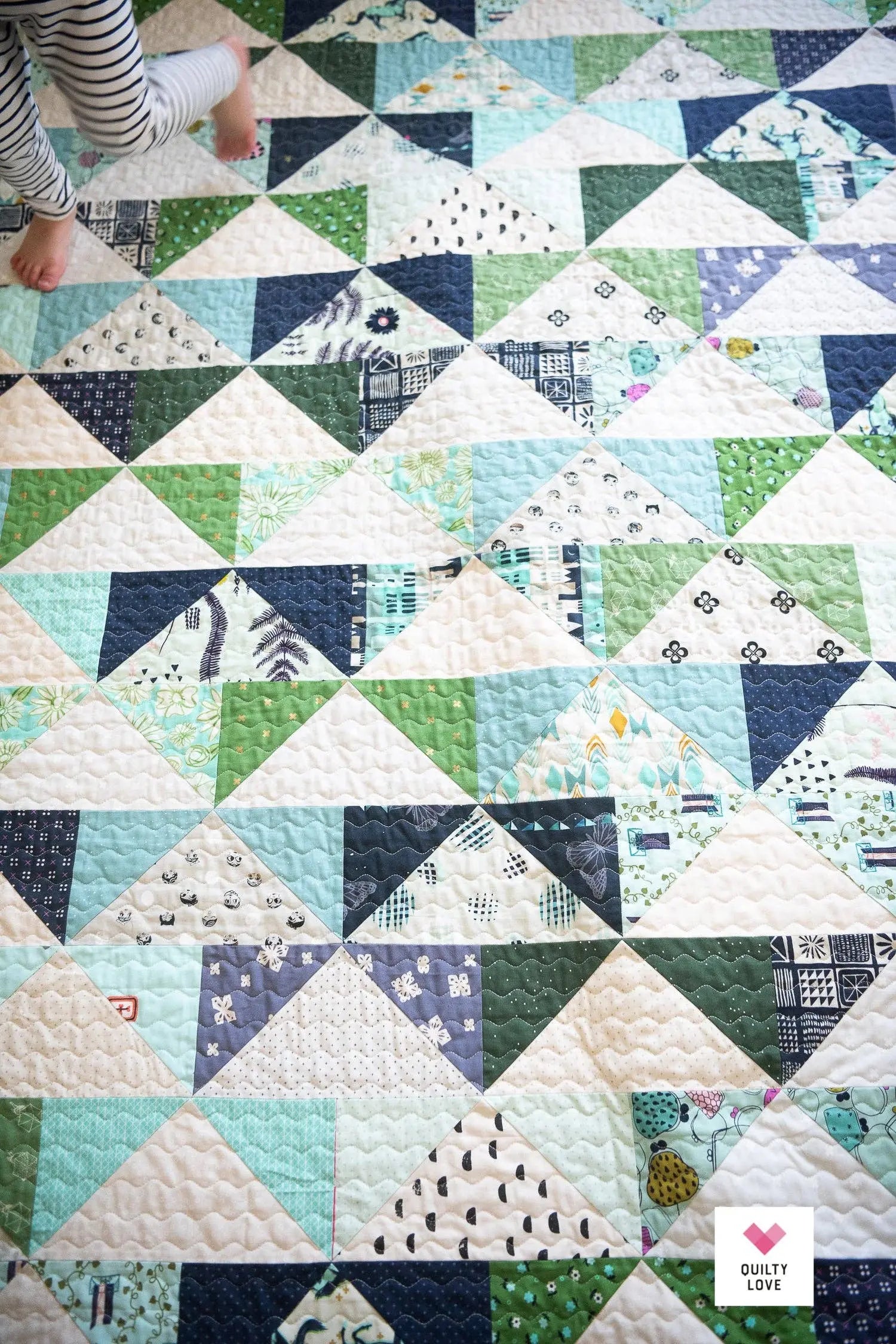 Quilt with triangle pattern featuring various colors and designs.