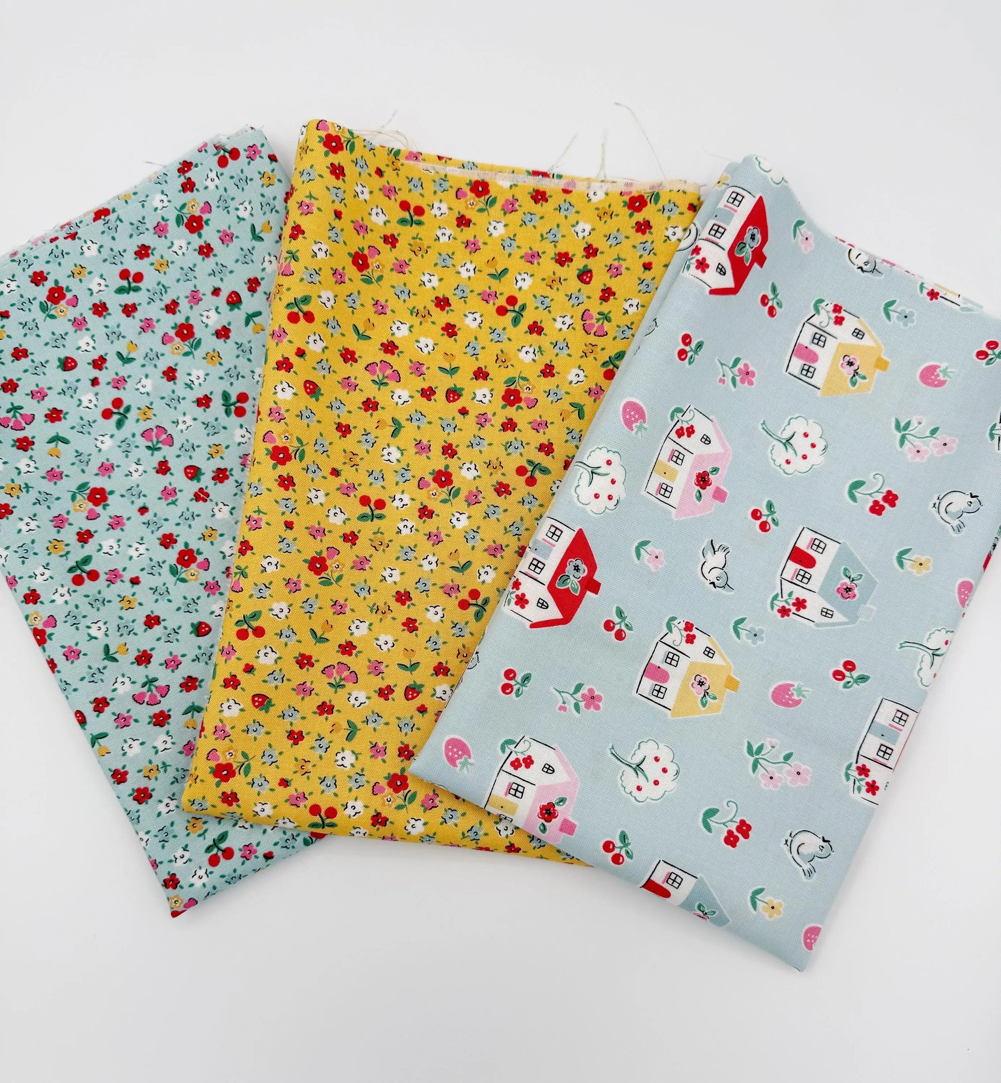 Three fabric swatches with floral and house patterns on a white background