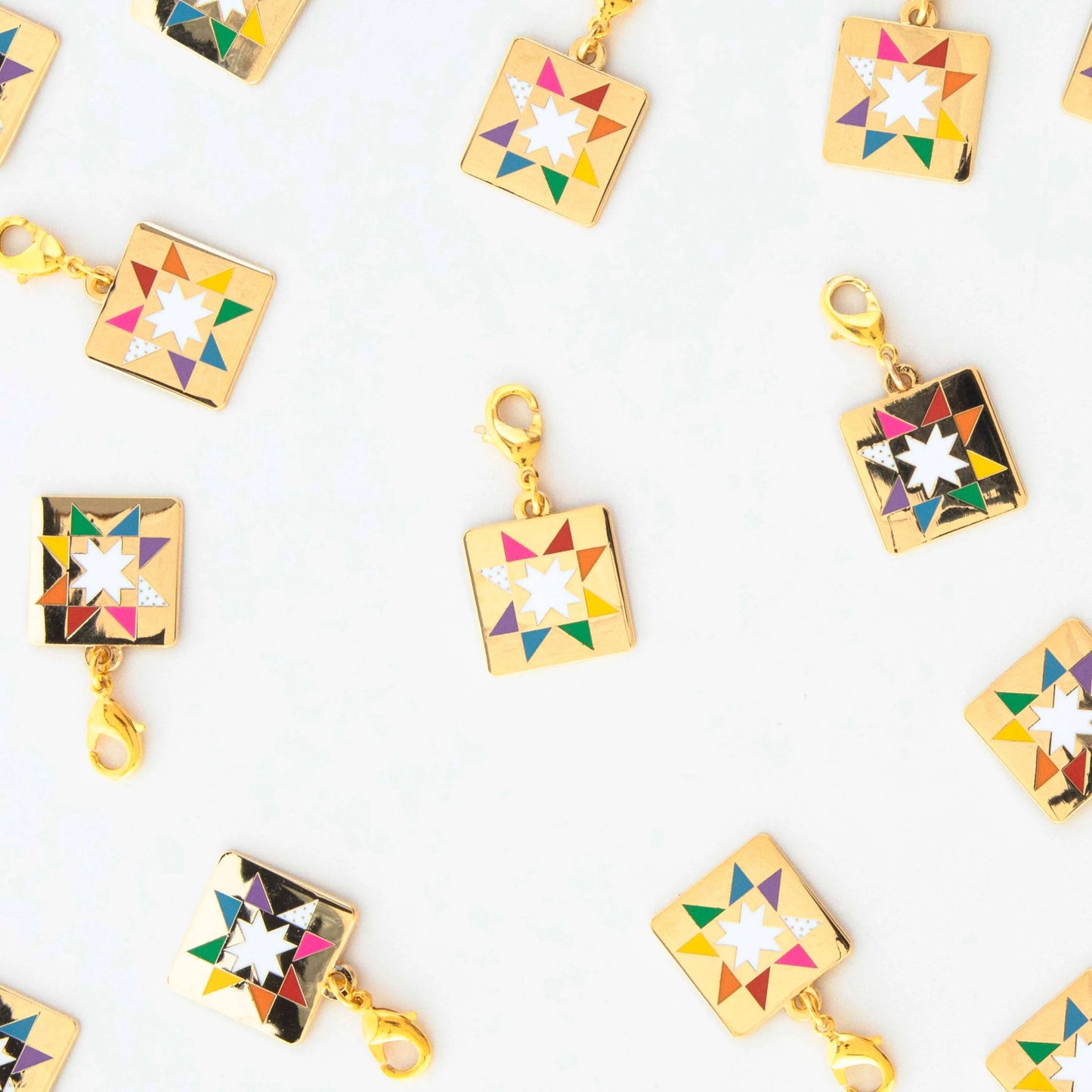 Colorful square-shaped zipper pull charms with quilt star designs on a white background