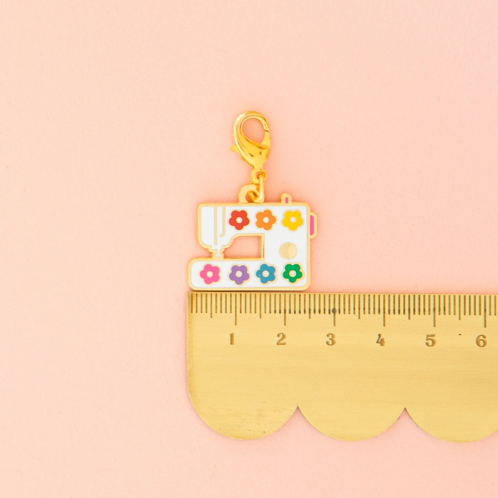 Sewing machine charm with colorful details on a pink background
