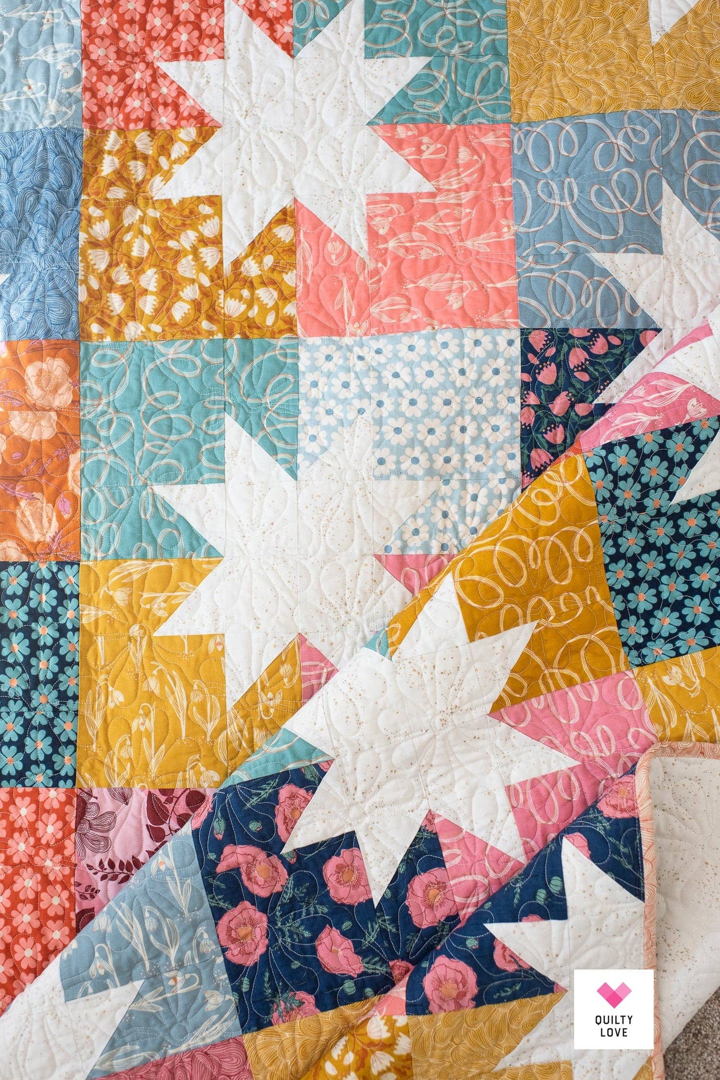 Colorful quilt with star patterns and 'Quilty Love' branding.