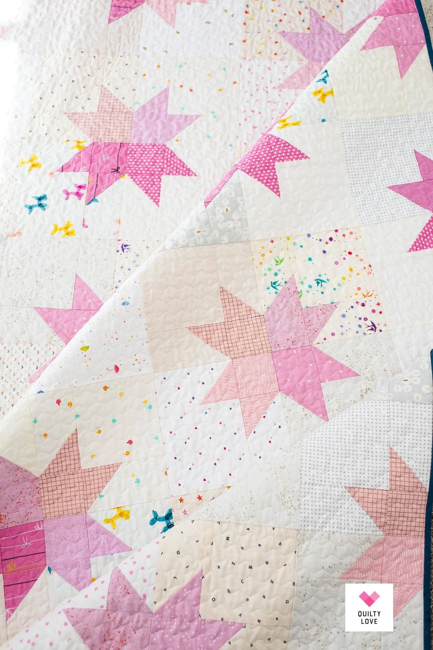 Quilt with pink star patterns on a white background