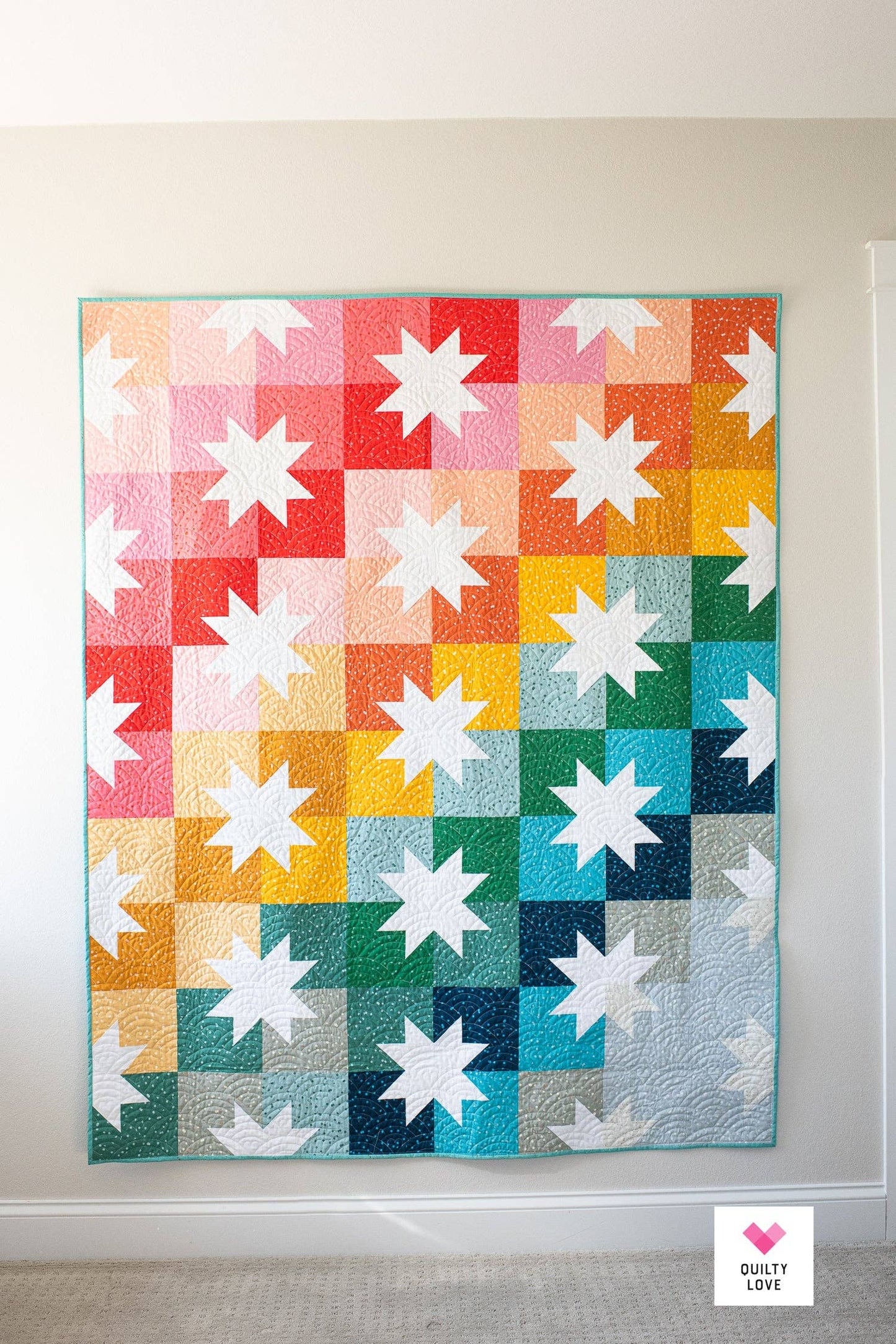 Colorful star-patterned quilt hanging on a wall.