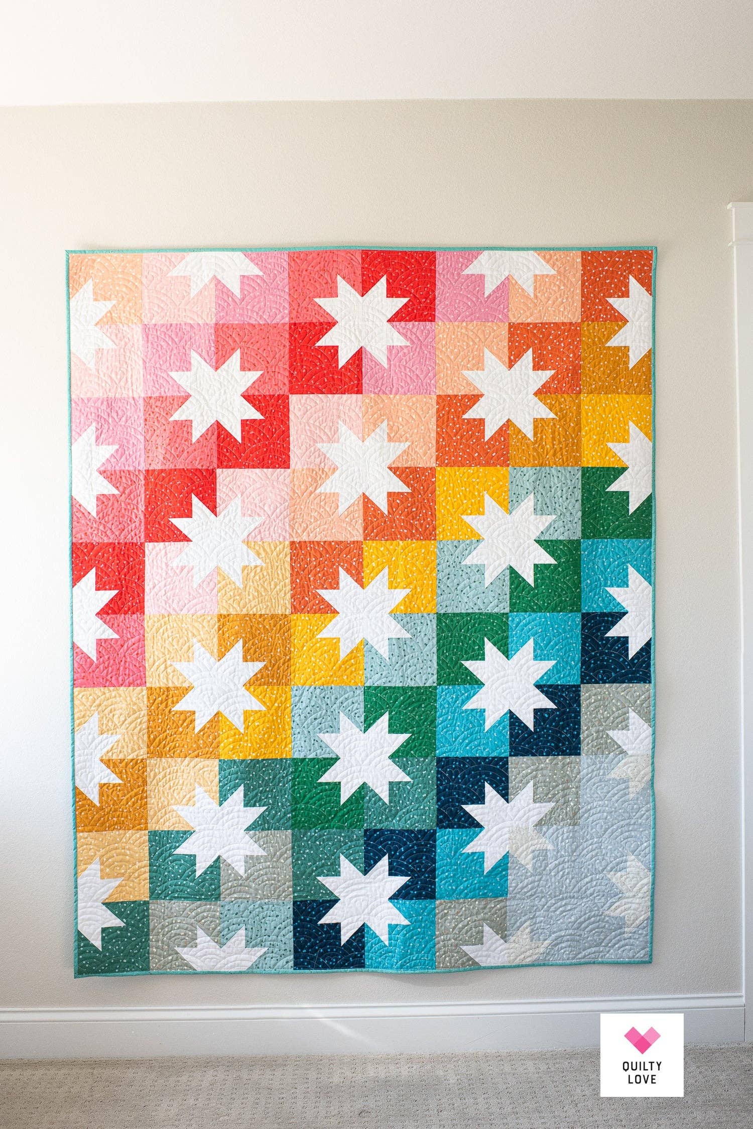 Colorful star-patterned quilt hanging on a wall.