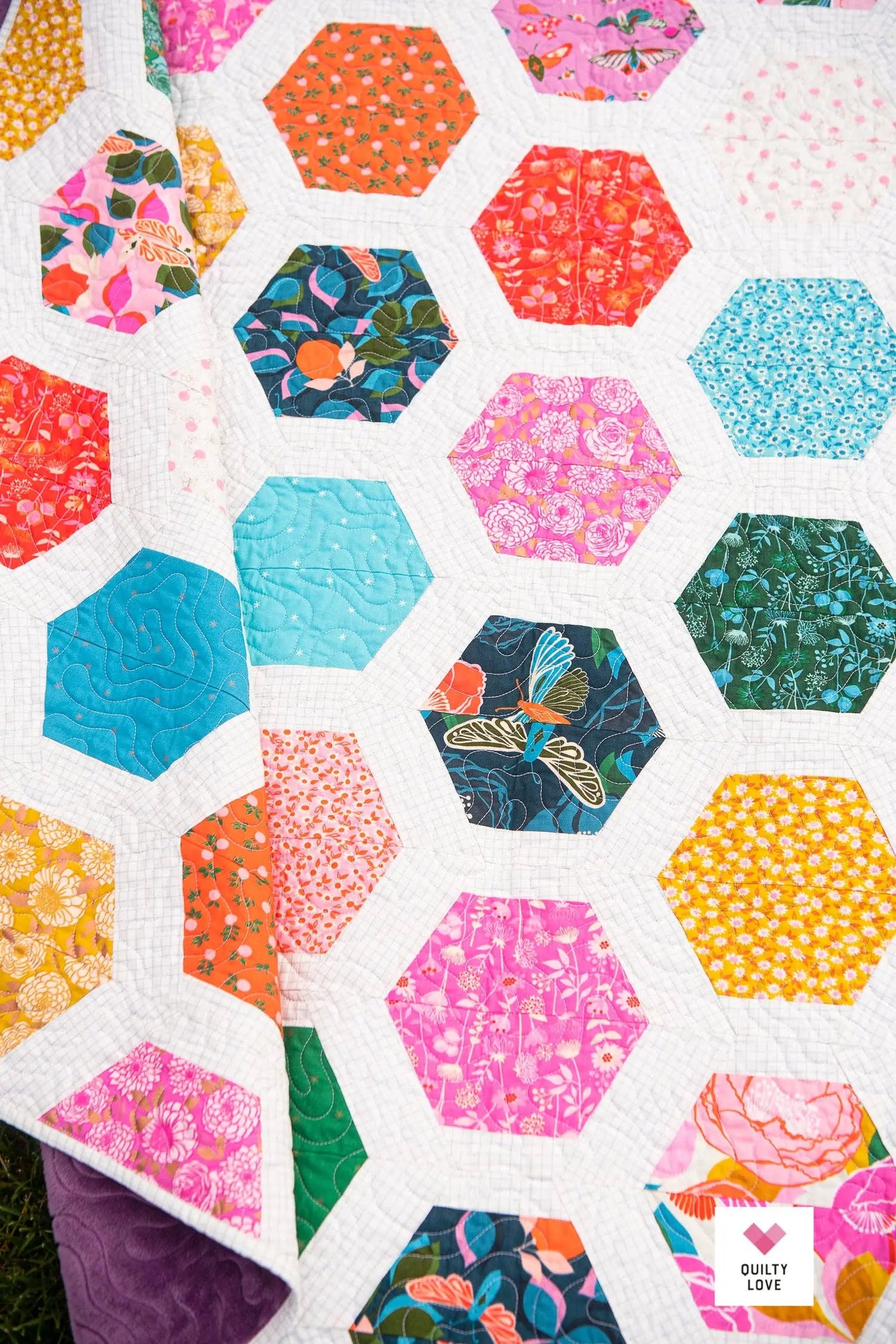 Hexagonal patchwork quilt with colorful floral patterns on a white background